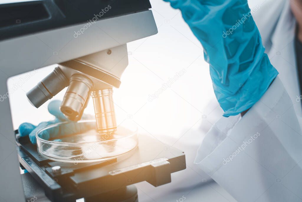 close-up female medical researcher looking at a microscope in a medical laboratory. Medical experimental concept