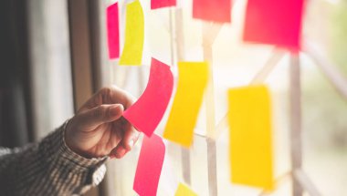 El, cam duvara iliştirdiği direği tutuyor. Beyin fırtınasını kavra, fikri paylaş.