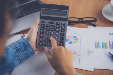 Muhasebecinin eli hesap makinesini kullanıyor. Maliyet analizi için kar ve zarar ve vergi hesaplama konsepti finansal açıklamaların hazırlanması