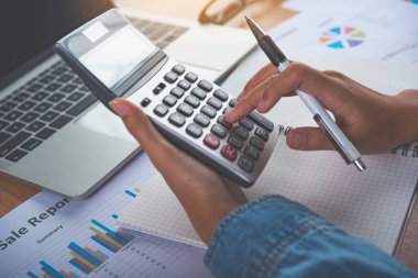 Muhasebecinin eli hesap makinesini kullanıyor. Maliyet analizi için kar ve zarar ve vergi hesaplama konsepti finansal açıklamaların hazırlanması