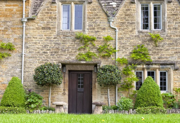 Velha aldeia inglesa casa de pedra com portas castanhas de madeira e gramado na frente — Fotografia de Stock