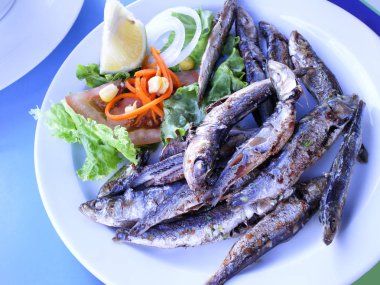 Salata ile servis beyaz plaka üzerinde ızgara balık