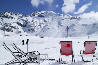 Apres ski in French alpine winter resort, chairs in front of snow track clipart