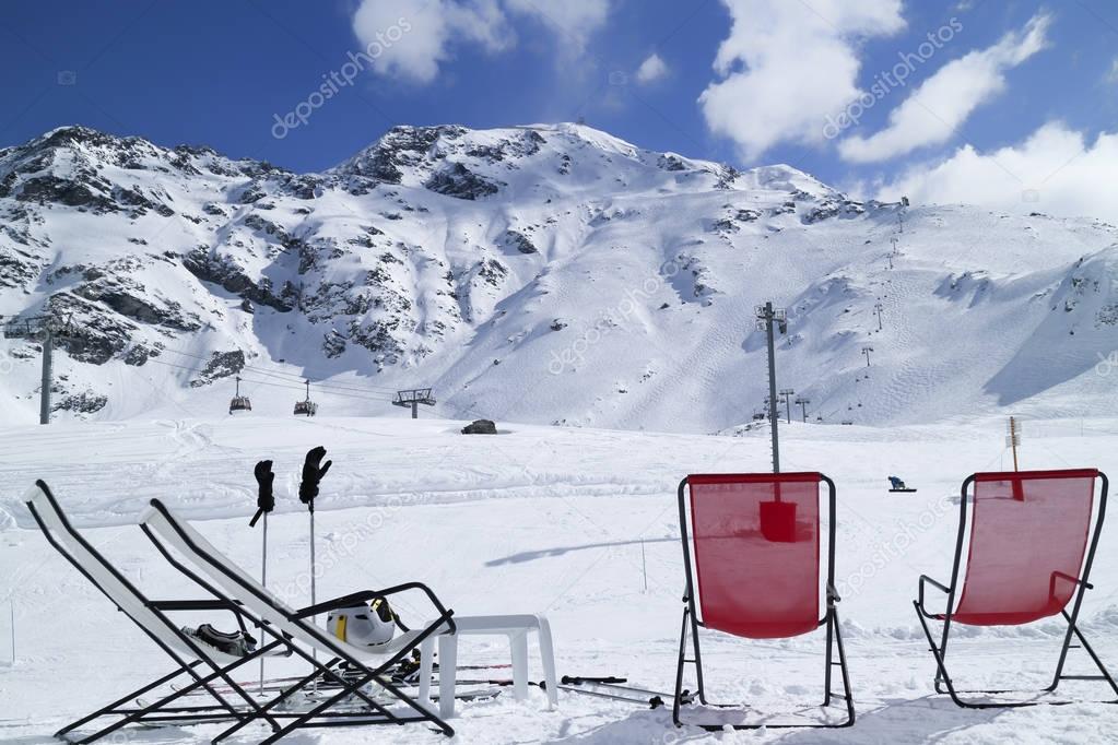 Apres ski in French alpine winter resort, chairs in front of snow track