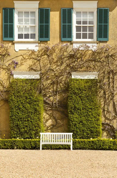 Wit bankje tussen groene hedge voor een huis — Stockfoto