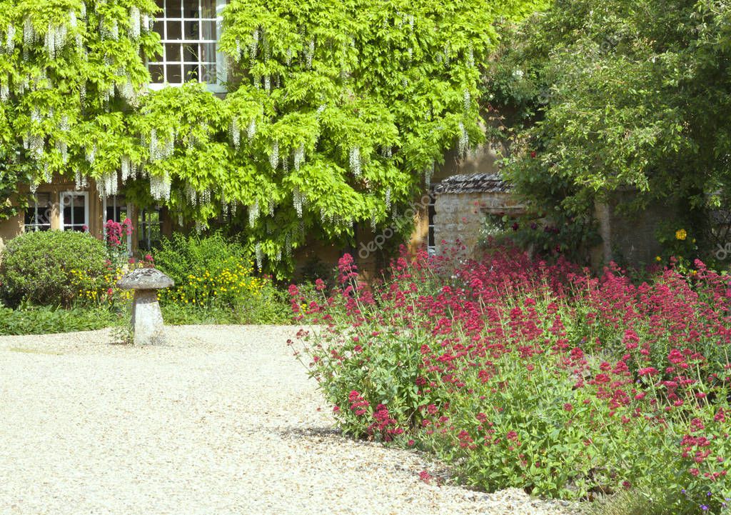 Stone driveway with front garden in bloom .