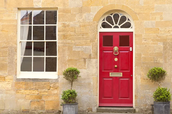 Rød dør i et gyllent engelsk hus av stein – stockfoto