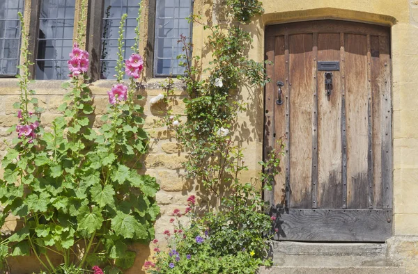 Puertas de la casa en una casa de campo Inglés con flores de colores en frente —  Fotos de Stock