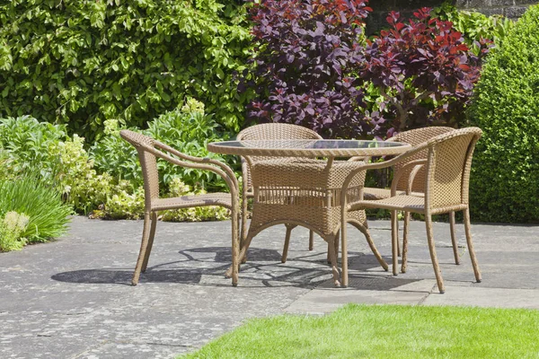 Patio chairs and table in a summer garden .