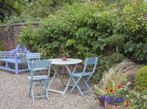 Salon de jardin bleu entre fleurs, plantes et arbres  . — Photo