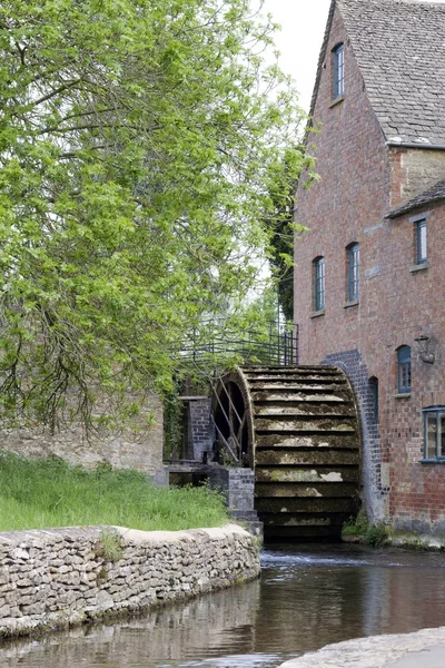 Old water mill in an English countryside with big wooden water wheel