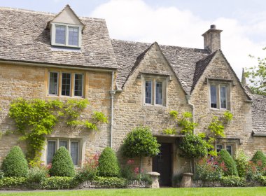 Çim bitkileri, renkli çiçekler önünde, Cotswolds, İngiltere'de kırsal köy ile kayrak çatı altın taş yazlık .