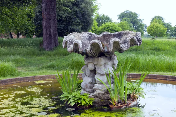 Stone water feature in a garden pond on the edge of rural English countryside, Cotswolds, UK .