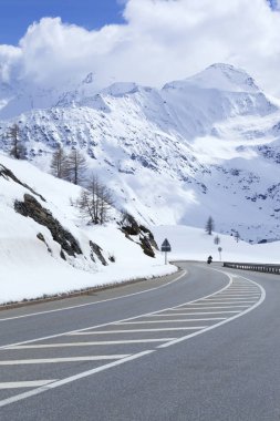 Dağlık tepeleri taze karla kaplı bir vadide asfalt yol. .