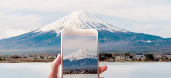 woman taking a picture of Mount Fuji with a smart phone.
