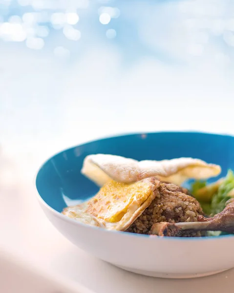 Ruh mavi bokeh arka plan üzerinde kızarmış pirinç bir kase yumurta kadar güneşli tarafı ile servis tavuk baget ve karides kraker. Cafe Restoran Yüzme Havuzu yanında alınan.