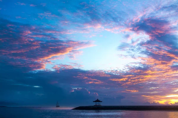 Pavilion and sailing boat during sunrise at sanur bali. Magic colorful cloudy sky before morning