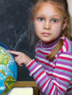 Kız - coğrafya dersi yakınındaki Dünya Dünya okul yönetimi arka planı üzerinde yedi yıllık bir çocuk