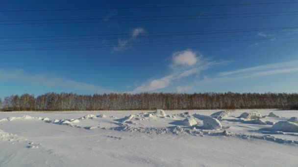 Qualidade vídeo trilhas de inverno na área siberiana em que caminhões de corrida e carros no fundo das profundas nevascas e um céu azul brilhante — Vídeo de Stock