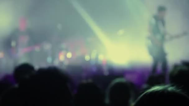 La multitud emocionada de espectadores aplaude frenéticamente a la popular banda de rock que actúa en el escenario — Vídeo de stock