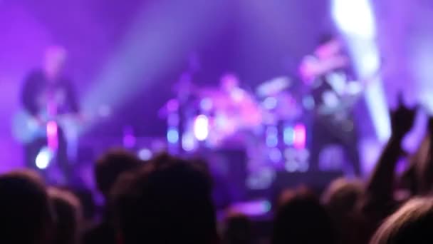 Возбужденная толпа зрителей неистово аплодирует популярной рок-группе, выступающей на сцене — стоковое видео