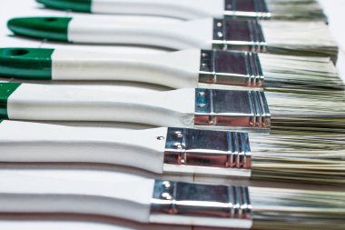 Boya fırçaları ve bir kavanoz dokulu bir ahşap masa üzerinde beyaz boya ile bir dizi beyaz boyalı