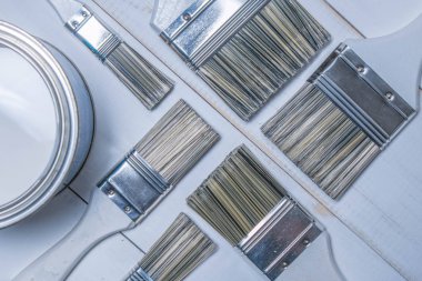 Boya fırçaları ve bir kavanoz dokulu bir ahşap masa üzerinde beyaz boya ile bir dizi beyaz boyalı