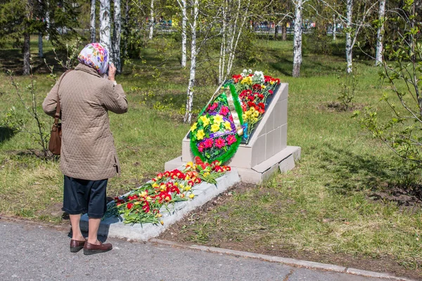 Den äldsta kvinnan lägger blommor på memorial plattan för att hedra de dödade soldaterna, på dagen för den stora segern 09.05.2017 Omsk — Stockfoto
