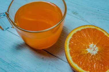 Bir bardak taze portakal suyu ile ahşap bir masa üzerine dilimlenmiş portakal. Taze portakal suyu hazırlanması
