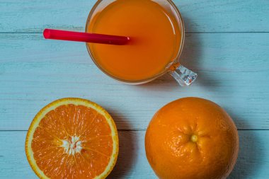 Bir bardak taze portakal suyu ile ahşap bir masa üzerine dilimlenmiş portakal. Taze portakal suyu hazırlanması