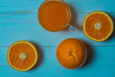 Bir bardak taze portakal suyu ile ahşap bir masa üzerine dilimlenmiş portakal. Taze portakal suyu hazırlanması