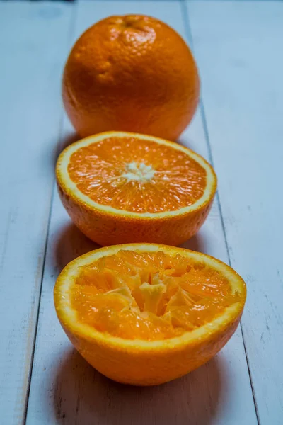 Ένα ποτήρι φρέσκο χυμό πορτοκαλιού με πορτοκάλια σε φέτες σε ένα ξύλινο τραπέζι. Προετοιμασία φρέσκο χυμό πορτοκαλιού — Φωτογραφία Αρχείου