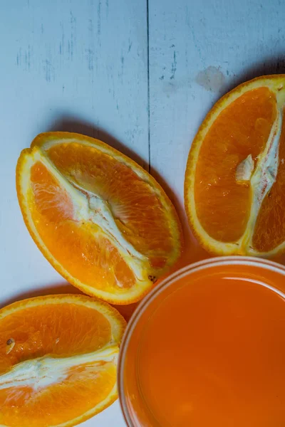 木製のテーブルにスライスしたオレンジとオレンジ ジュースのガラス。新鮮なオレンジ ジュースの準備 — ストック写真