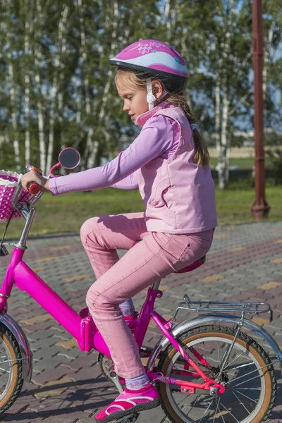 Mädchen mit rosa Helm fährt Fahrrad im Park — Stockfoto