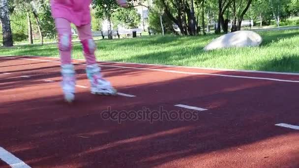 Uma menina de roupas rosa patina em um parque de patinação à noite — Vídeo de Stock