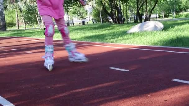 Uma menina de roupas rosa patina em um parque de patinação à noite — Vídeo de Stock