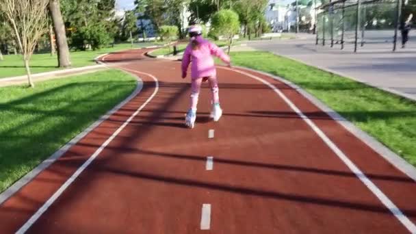 Una bambina di sette anni impara a pattinare in un parco estivo su una pista ciclabile — Video Stock