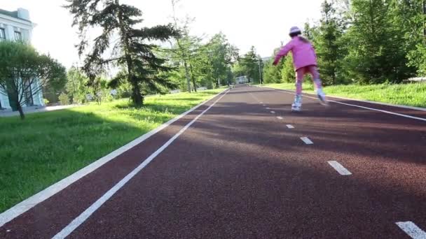 A girl of seven years old learns to skate in the park on a bicycle path — Stock Video