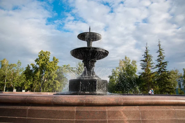 Large granite fountain in a city park on a background of a bright blue sky — Stock Photo, Image