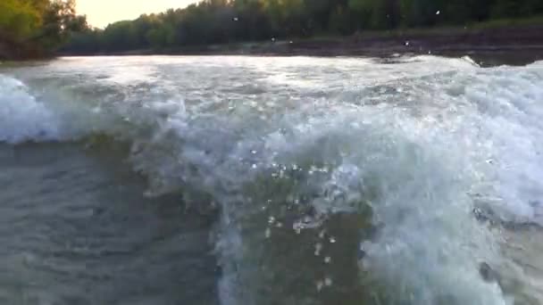 Wake from the propeller of a boat moving on a dull desert the river along steep banks — Stock Video