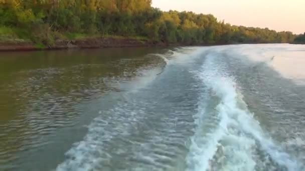 Réveillez-vous de l'hélice d'un bateau se déplaçant sur un désert terne la rivière le long des rives escarpées — Video