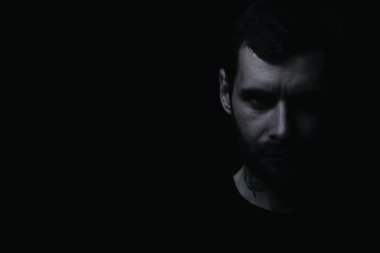 Dokulu bir yüz siyah bir arka plan ile bir sakallı genç acımasız adam portresi. Çerçeve serbest metinli müşteri sol tarafında