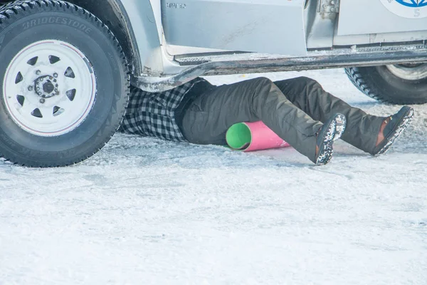 Mechanic repairs his SUV under the car in the cold in winter — Stock Photo, Image