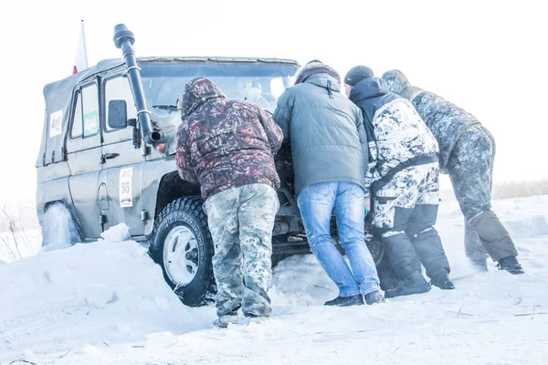 Ein paar Männer schieben auf dem sibirischen Geländewagen-Wettbewerb 2018 ein Auto aus einer Schneewehe — Stockfoto