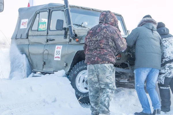 Pár mužů tlačit auto ze závěje sněhu na Sibiřské soutěž Suv 2018 — Stock fotografie