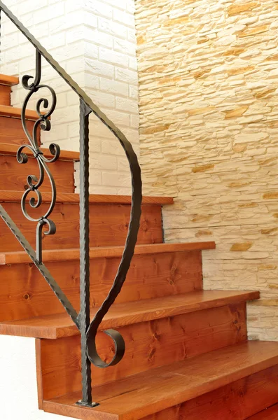 Wooden interior stairway with ornamental ironwork railing — Stock Photo, Image