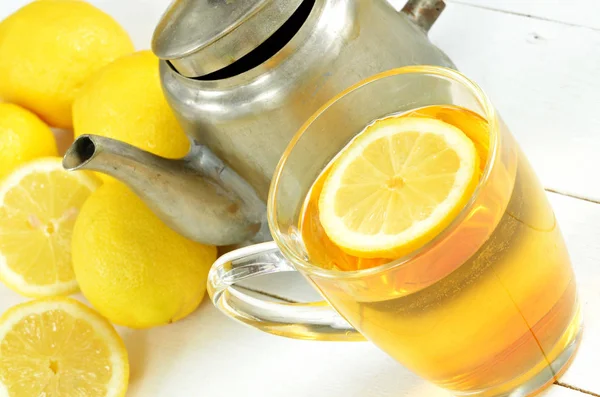Черный чай с ломтиком лимона в кружке, старый чайник и лимоны — стоковое фото