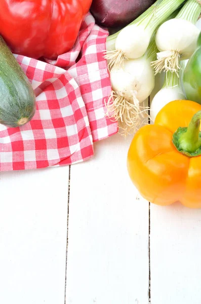Перец, лук, цуккини, весенний лук и полотенце на столах — стоковое фото