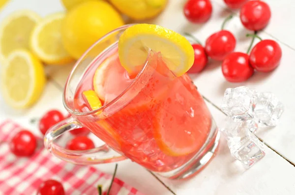Фруктовый вишневый чай со льдом с ломтиком лимона в кружке и вишней — стоковое фото