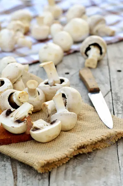 Schneiden von Champignons auf einem hölzernen Schneidebrett und einem Sacktuch — Stockfoto